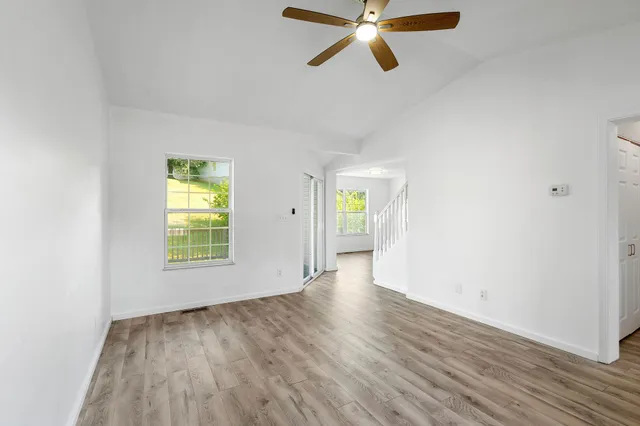 a view of an empty room with a window and wooden floor