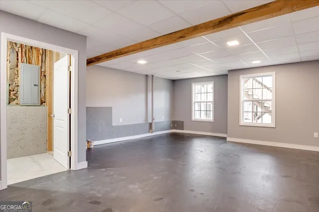 an empty room with wooden floor and windows with curtains