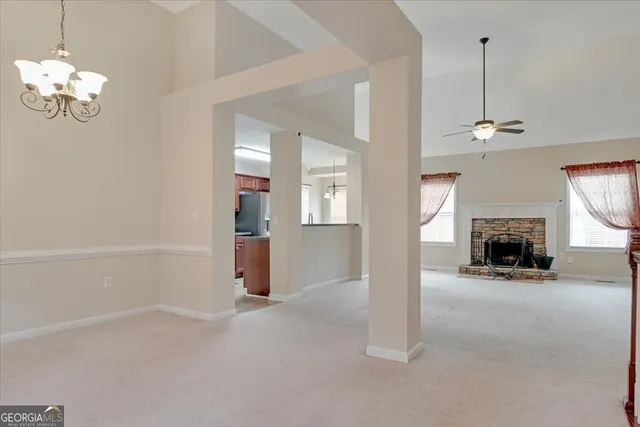 a view of a livingroom with a fireplace a chandelier and windows