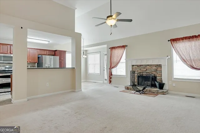 a view of a livingroom with a fireplace a ceiling fan a fireplace and windows