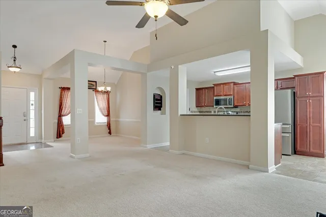 a view of a room with a ceiling fan and refrigerator