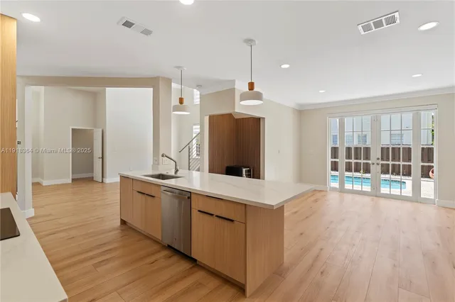 a large white kitchen with a large window a sink and stainless steel appliances