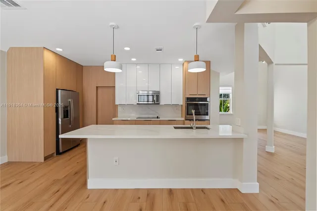 a large kitchen with stainless steel appliances a large counter top a refrigerator a sink and a stove