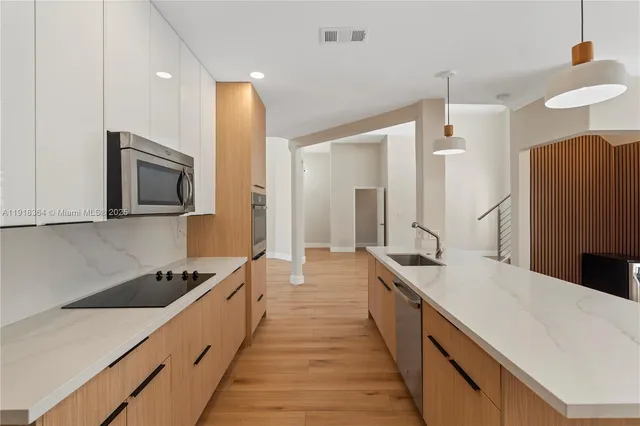 a large kitchen with stainless steel appliances a sink and cabinets