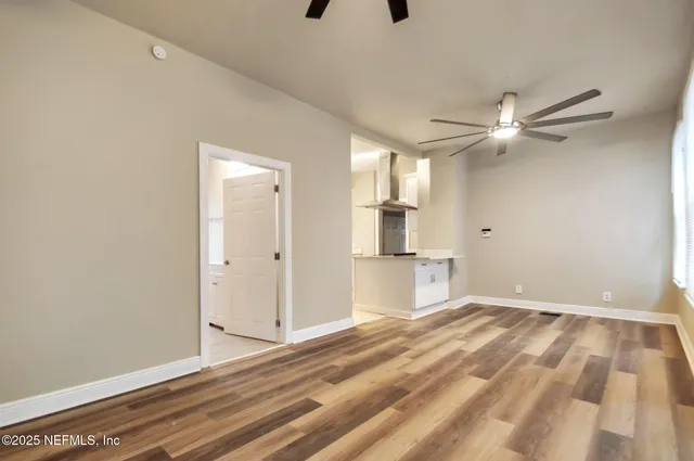 a view of empty room with wooden floor and fan