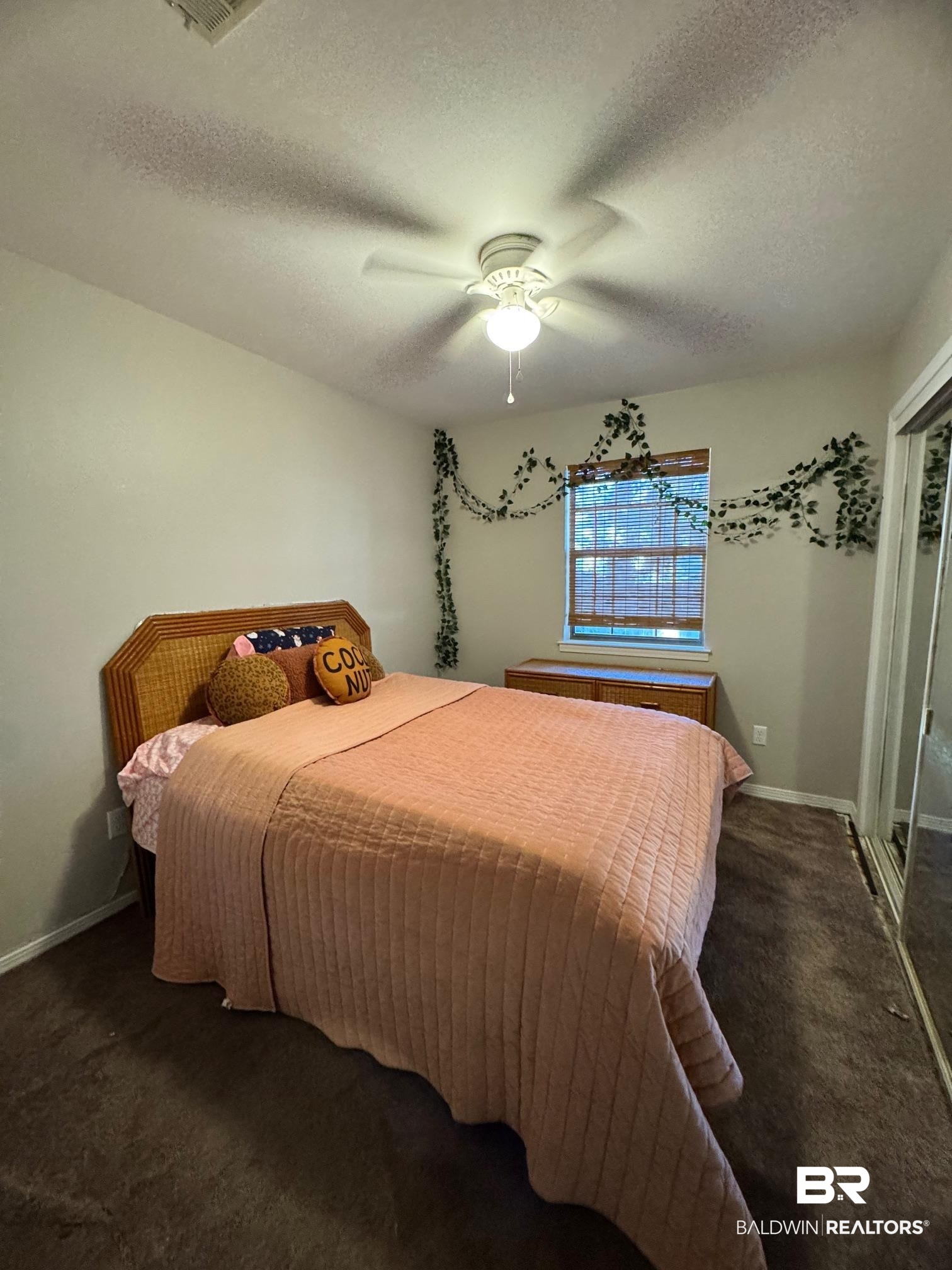 1434 Ridgewood Drive Lillian, AL 36549 - Photo 19 of 45 Bedroom with ceiling fan, a textured ceiling, and dark colored carpet