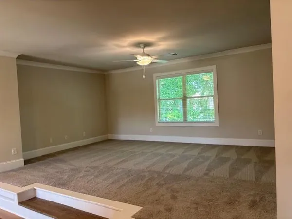 an empty room with a chandelier fan and windows