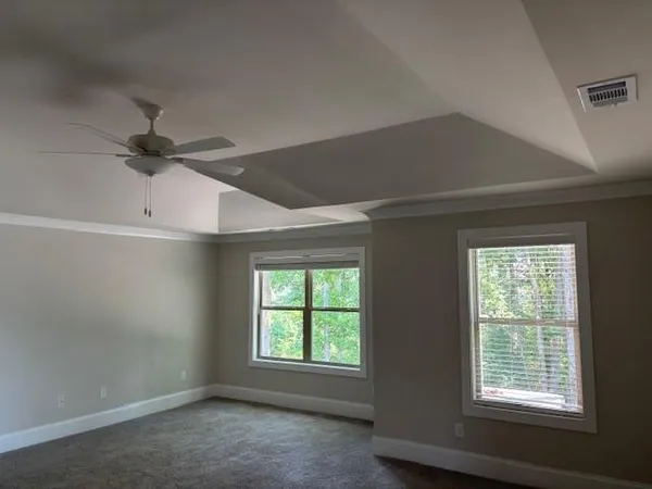 an empty room with windows and ceiling fan