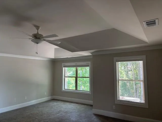 an empty room with windows and ceiling fan