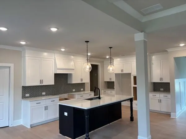 a kitchen with center island sink and cabinets