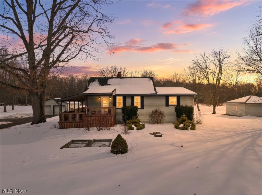 View of front of property featuring an outdoor structure, a garage, a chimney, and a wooden deck