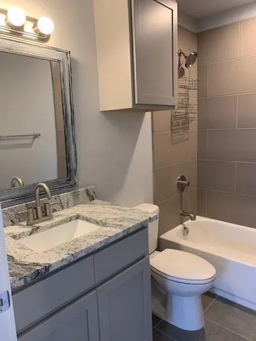 a bathroom with a granite countertop toilet sink and mirror
