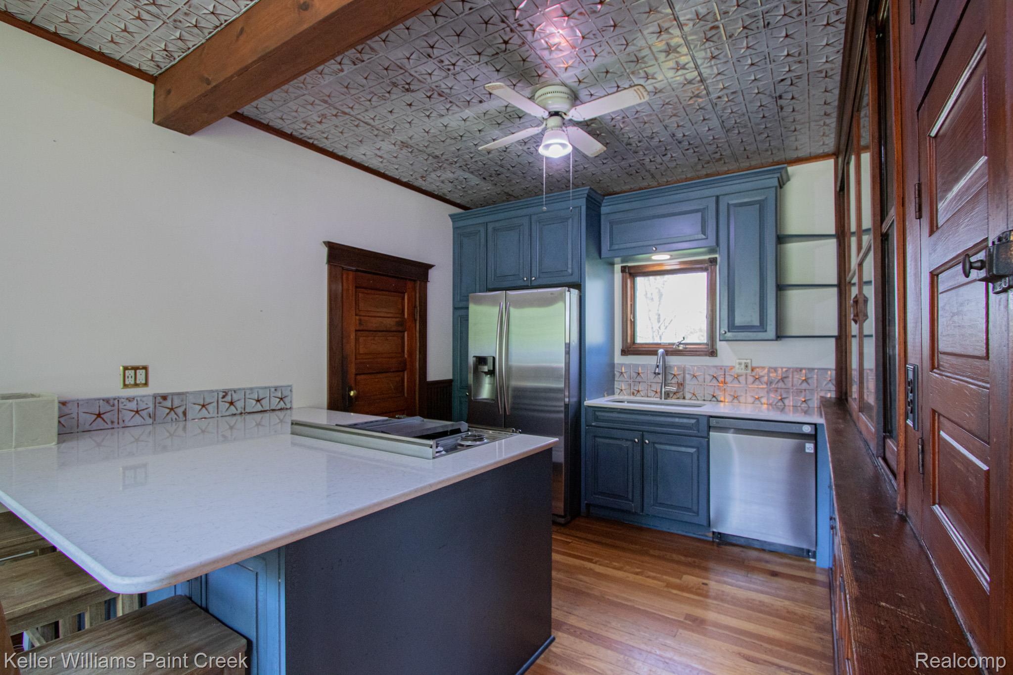 Kitchen with a kitchen breakfast bar, stainless steel appliances, a peninsula, ceiling fan, and dark wood-style floors