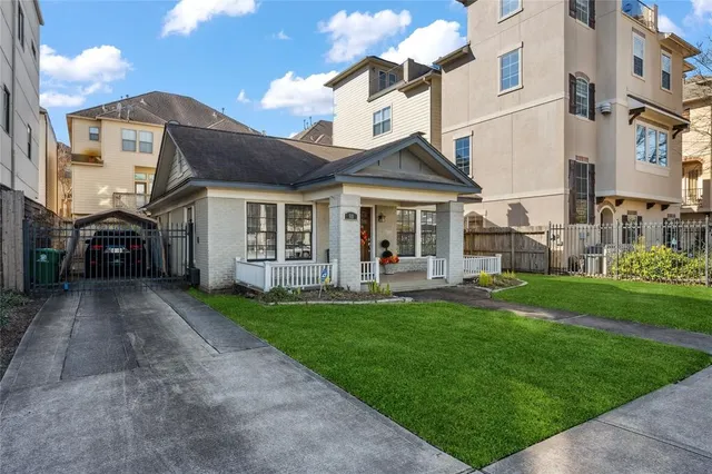 a view of a white house next to a yard with big trees