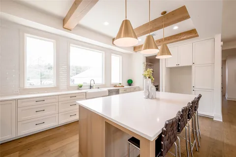 a large kitchen with kitchen island a stove a sink a dining table and chairs with wooden floor