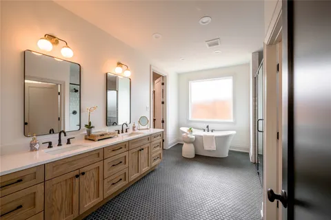 a bathroom with double vanity sinks a large mirror and a bathtub