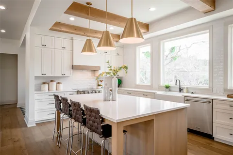 a kitchen with stainless steel appliances kitchen island a table chairs in it and wooden floors