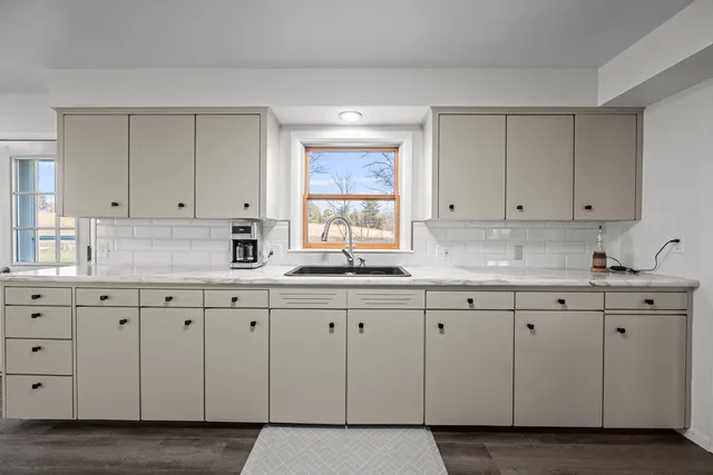 a kitchen with granite countertop white cabinets and sink