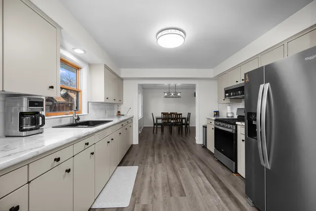 a large kitchen with a center island wooden floor stainless steel appliances and cabinets
