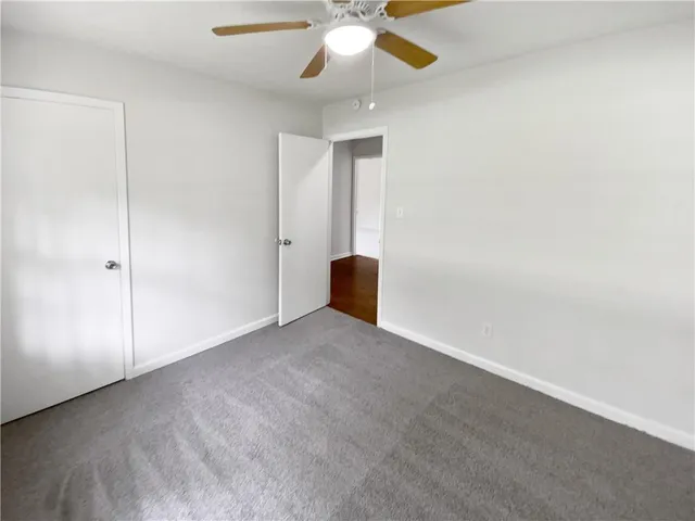an empty room with closet and a ceiling fan