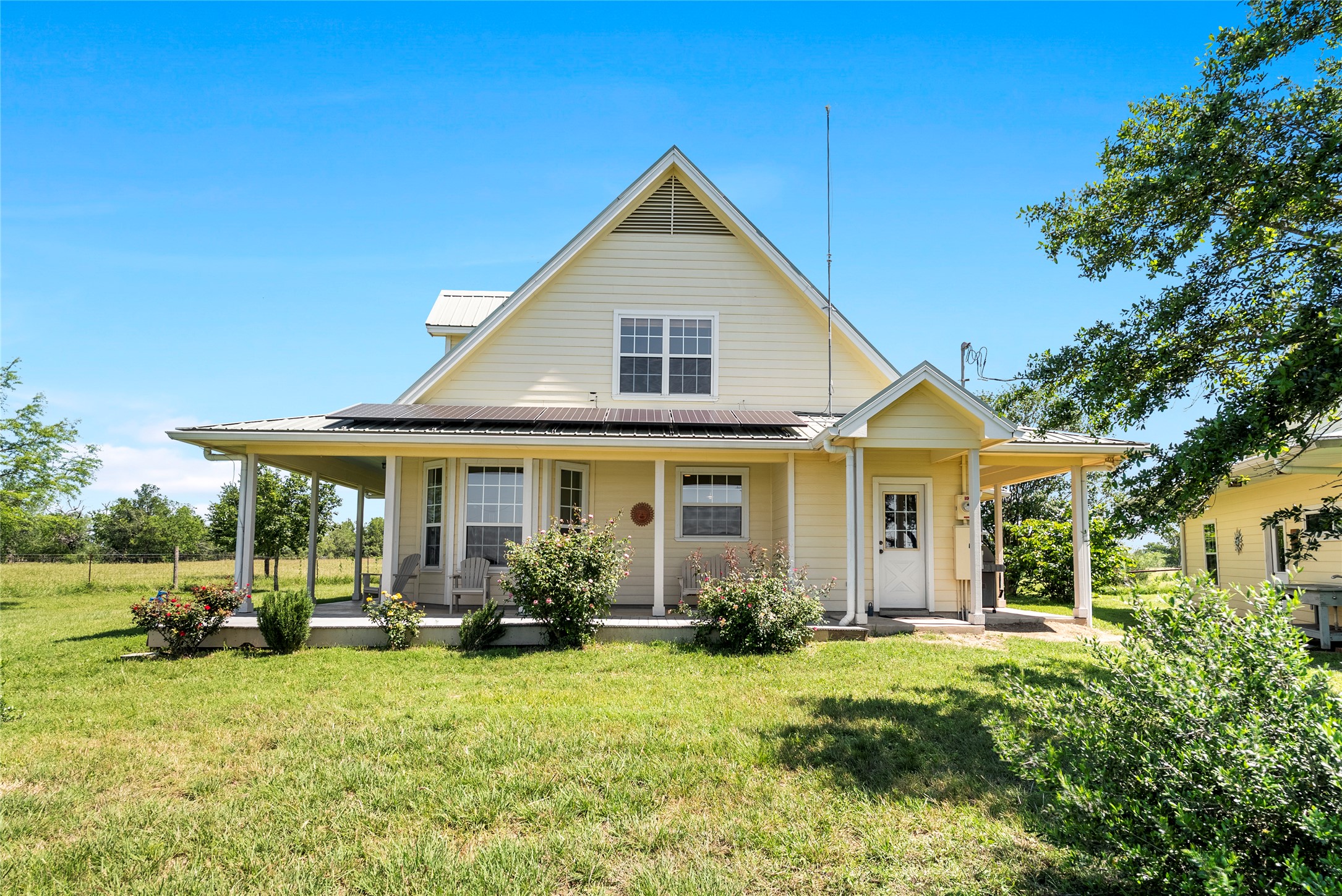 928 Upper Elgin River Road Elgin, TX 78621 - Photo 6 of 40 Farmhouse-style exterior with a full-width covered front porch, white metal roof, & solar panels