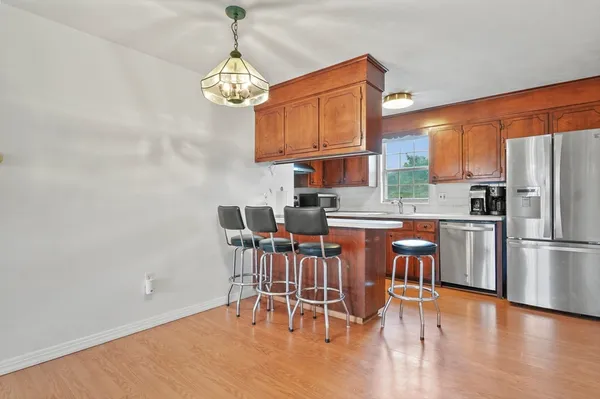 a kitchen with stainless steel appliances granite countertop a dining table chairs sink refrigerator and microwave