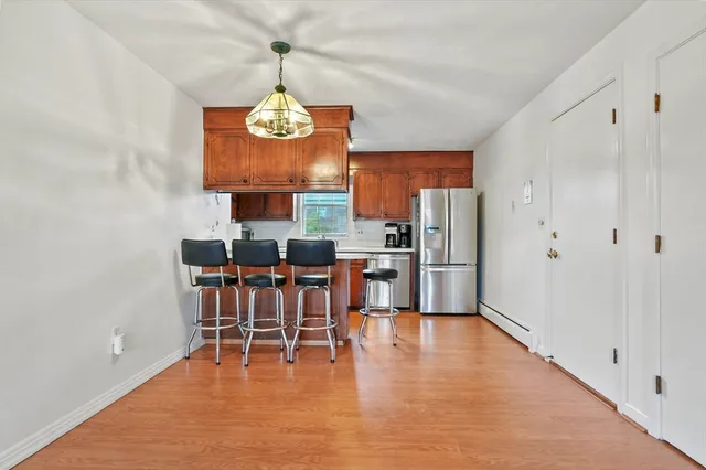 a dining room with stainless steel appliances a wooden floor a dining table and chairs
