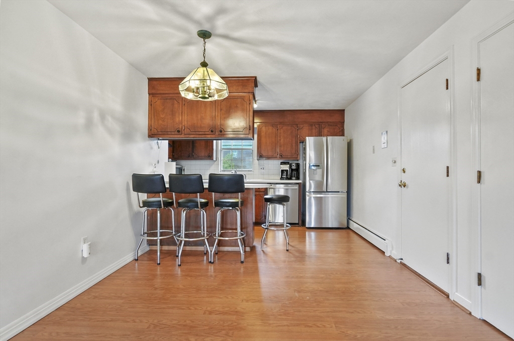 132 Parker Street, Unit G5 Acton, MA 01720 - Photo 5 of 22 a dining room with stainless steel appliances a wooden floor a dining table and chairs