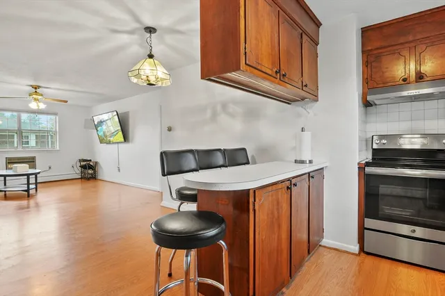 a kitchen with stainless steel appliances a stove a chandelier a dining table and chairs