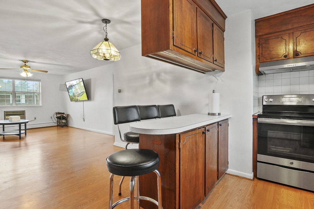 132 Parker Street, Unit G5 Acton, MA 01720 - Photo 8 of 22 a kitchen with stainless steel appliances a stove a chandelier a dining table and chairs