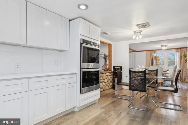 a kitchen with stainless steel appliances granite countertop a stove and white cabinets with wooden floor