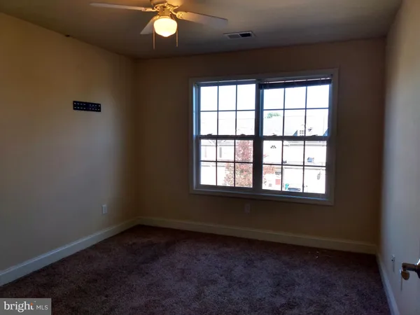 an empty room with a window and a fan