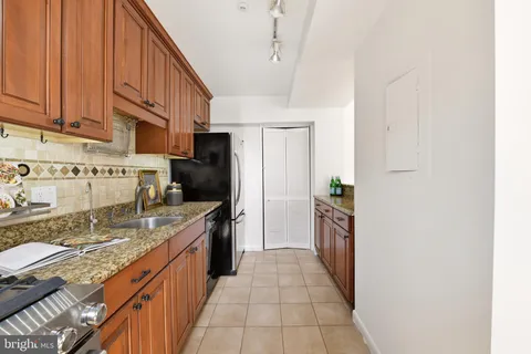 a kitchen with stainless steel appliances granite countertop a refrigerator a stove and a sink