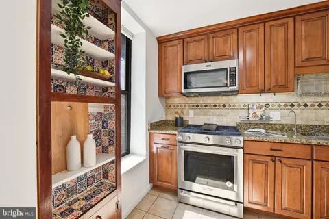a kitchen with granite countertop a stove top oven microwave and cabinets