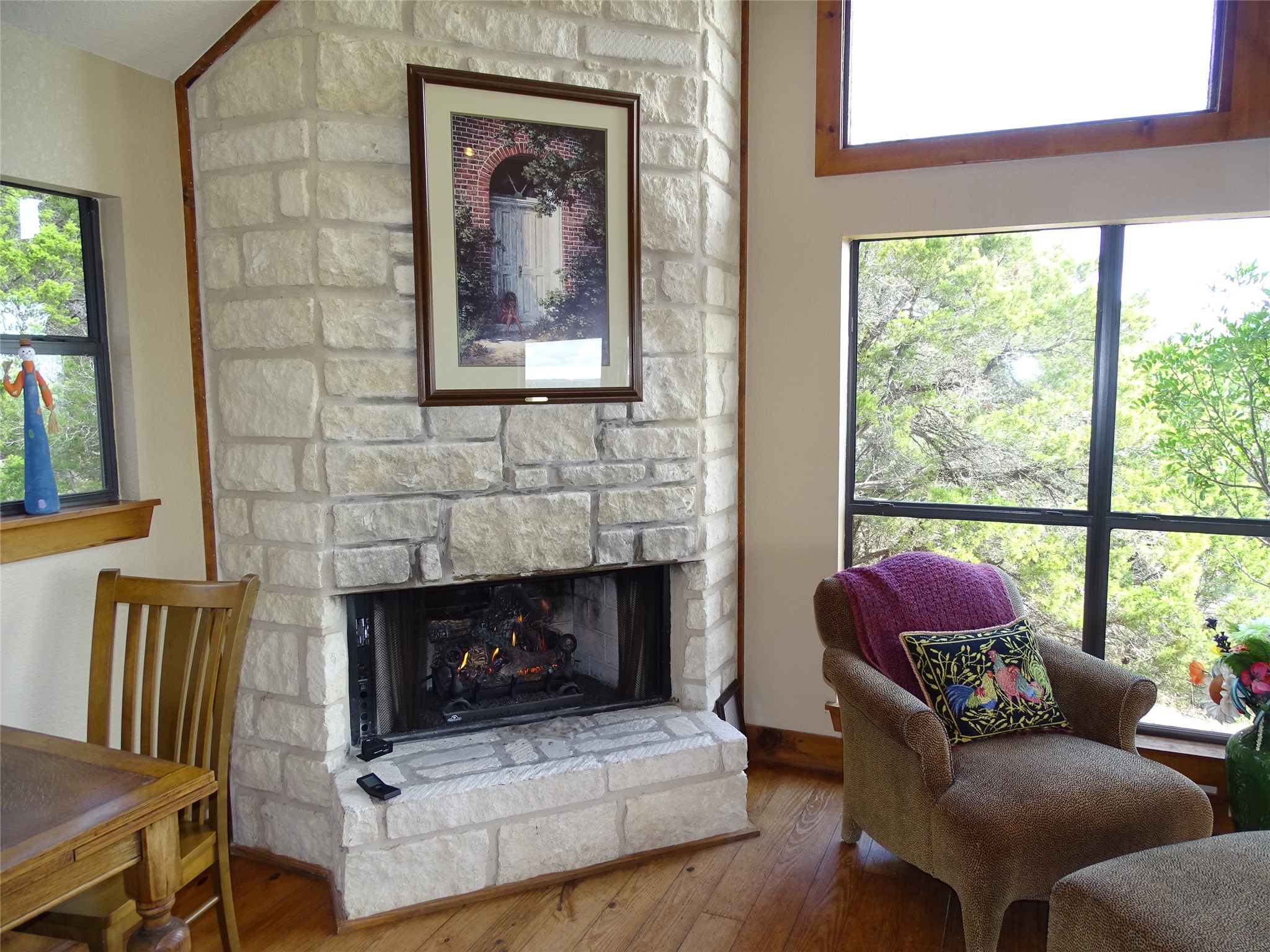 919 Little Ranches Road Wimberley, TX 78676 - Photo 5 of 13 A striking stone fireplace creates a focal point in this inviting living space, complemented by a serene woodland view.