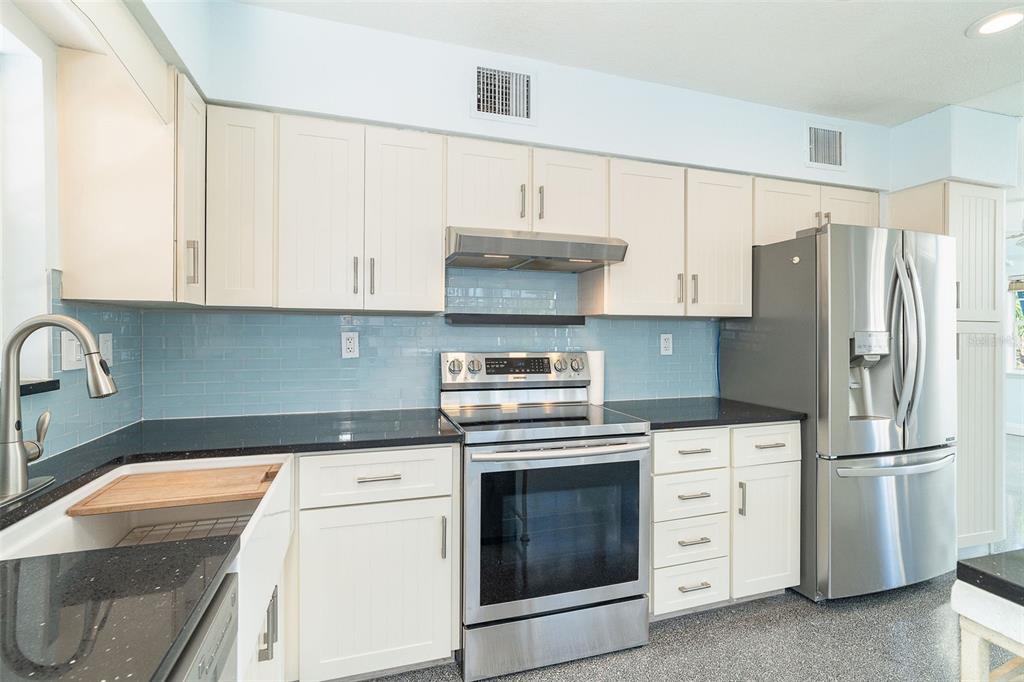 2835 North Beach Road, Unit A Englewood, FL 34223 - Photo 15 of 58 a kitchen with granite countertop white cabinets and stainless steel appliances