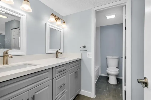 a bathroom with a granite countertop sink a toilet and a mirror