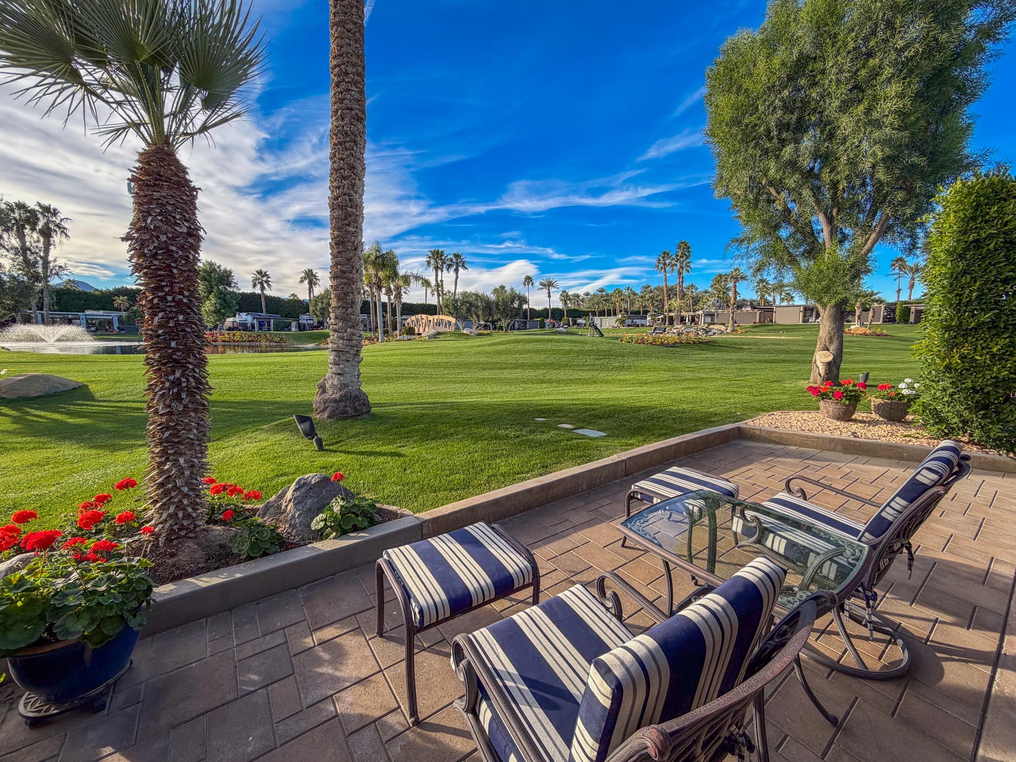 80394 Ave 48, Unit 298 Indio, CA 92201 - Photo 11 of 25 a view of a patio with lawn chairs floor to ceiling window and a yard