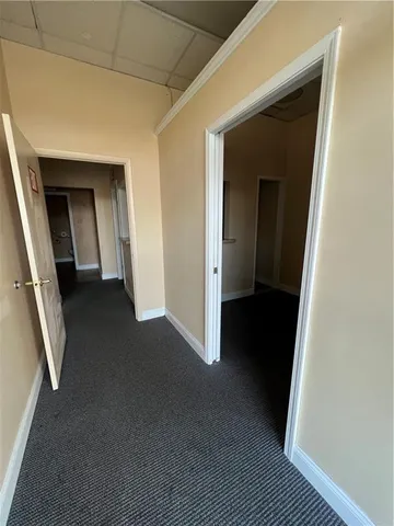 a view of a hallway to an empty room with wooden floor and a window