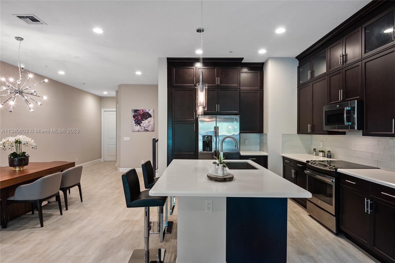 22936 Clear Echo Drive, Unit 34 Boca Raton, FL 33433 - Photo 6 of 41 a kitchen with stainless steel appliances kitchen island granite countertop a sink a stove a dining table and chairs