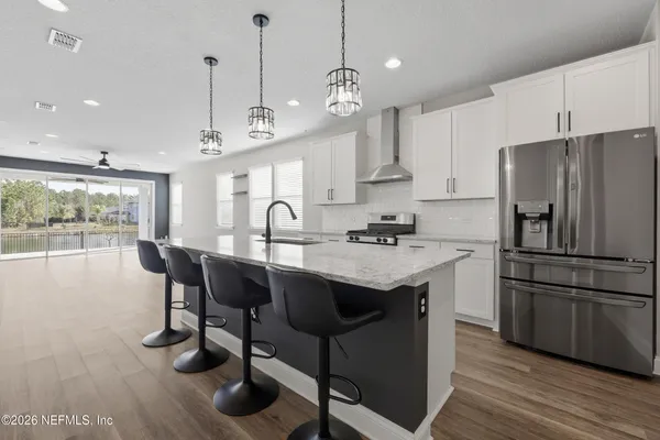 a kitchen with stainless steel appliances granite countertop a sink a stove a refrigerator and island with wooden floor