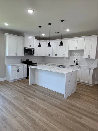 a large kitchen with stainless steel appliances granite countertop a stove a sink dishwasher and a refrigerator with wooden floor
