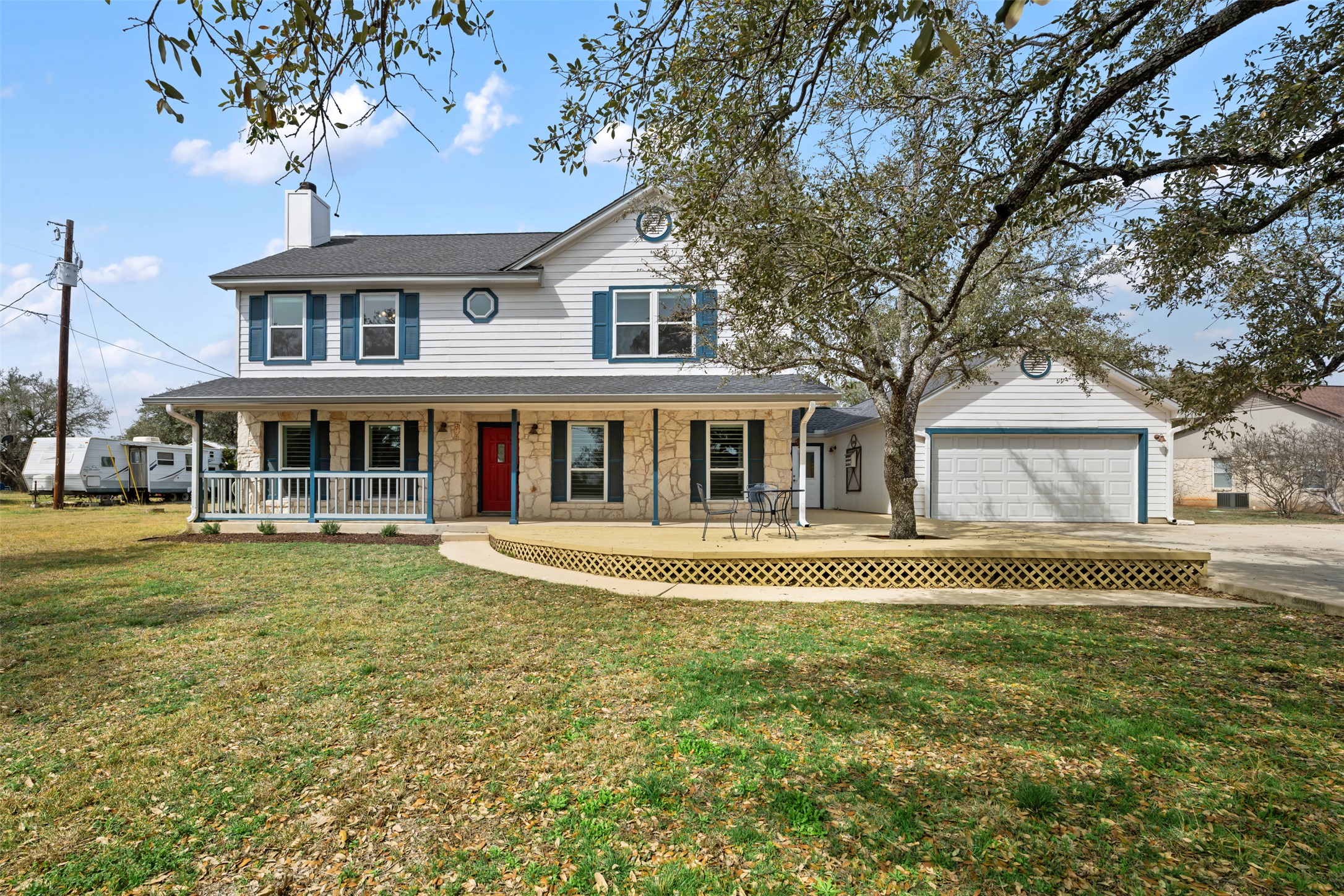 View of front of property featuring a porch, stone siding, a chimney, and a front lawn