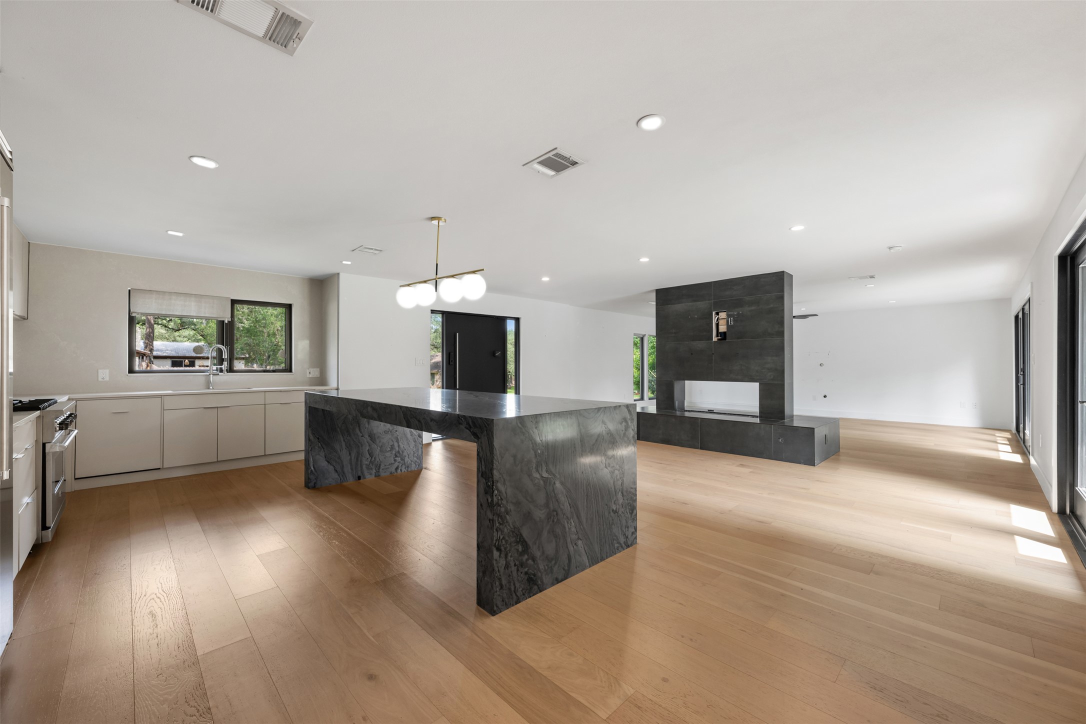 8900 Point W Drive Austin, TX 78759 - Photo 17 of 40 A luminous living space features an open-concept kitchen, elegant stone island, and a sleek fireplace.