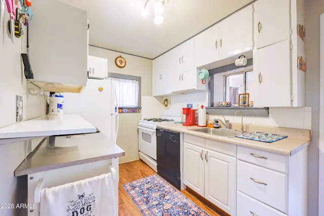 a kitchen with a stove a sink dishwasher and cabinets with wooden floor