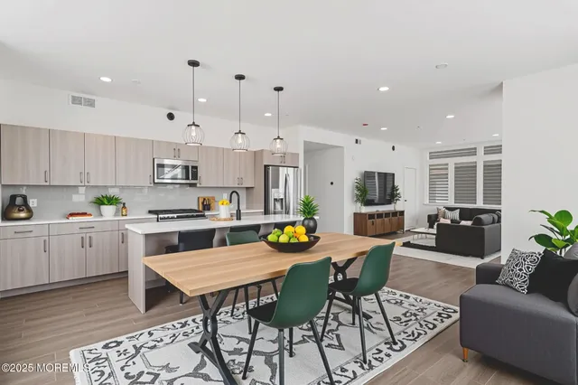 a living room with stainless steel appliances kitchen island a table and chairs in it