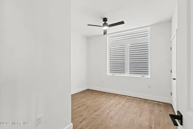 an empty room with a window and a ceiling fan