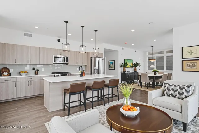 a kitchen with stainless steel appliances kitchen island granite countertop a stove a sink a dining table and chairs with wooden floor