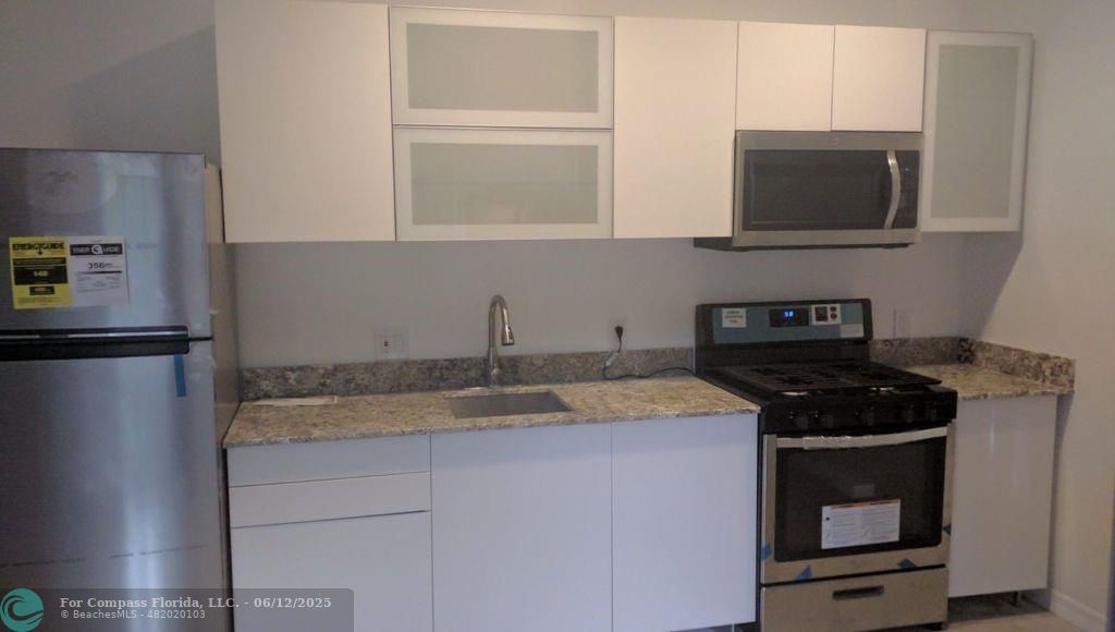 1611 Michigan Avenue, Unit 2 Miami Beach, FL 33139 - Photo 4 of 15 a kitchen with granite countertop stainless steel appliances a stove microwave and sink
