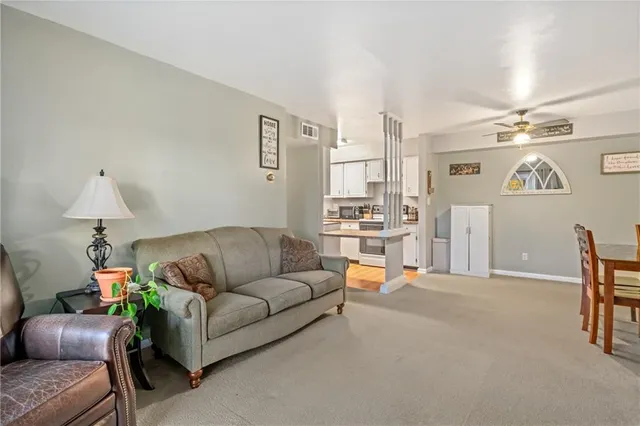 a living room with furniture and a dining table with projector the kitchen
